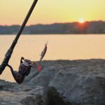 Angelrute an einem ruhigen See bei Sonnenaufgang