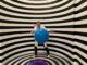 illuseum berlin - A man wearing a lab coat poses with a blue ball in a striped illusion room.