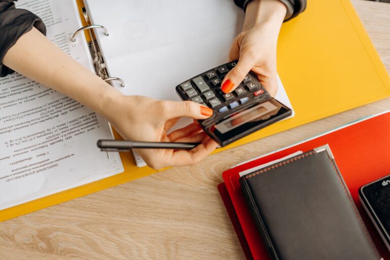 Schreibtisch im Homeoffice mit Unterlagen, Taschenrechner und Notebook