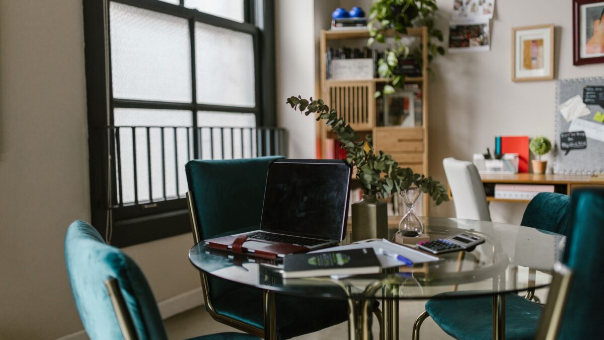 Arbeitsplatz im Homeoffice mit Laptop, Notizbuch und Kaffeetasse am Fenster