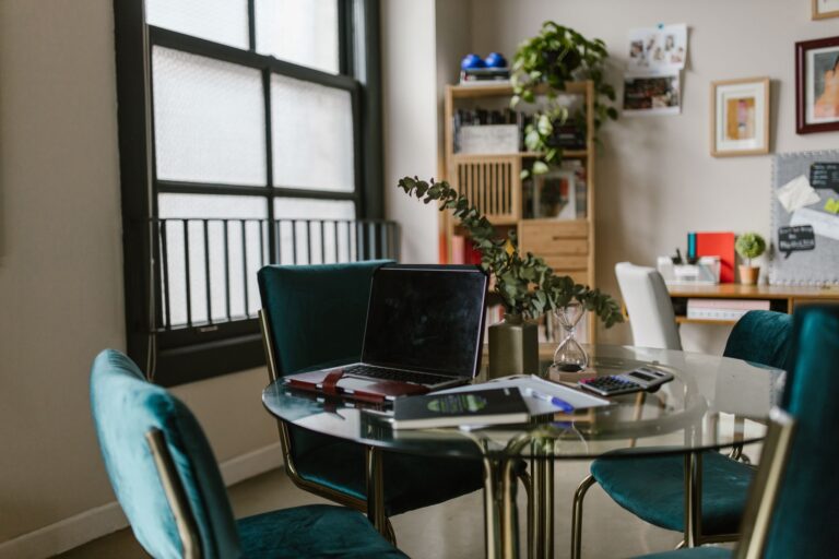 Arbeitsplatz im Homeoffice mit Laptop, Notizbuch und Kaffeetasse am Fenster